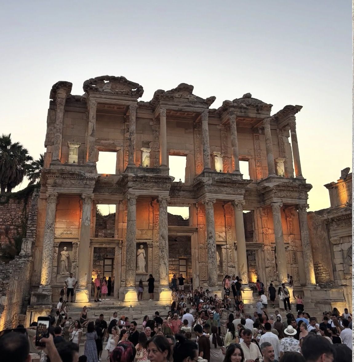Visitors exploring the ruins of the Library of Celsus in Turkey on a sunny morning